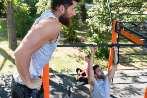 Mann trainiert draußen an einem Fitness Rack
